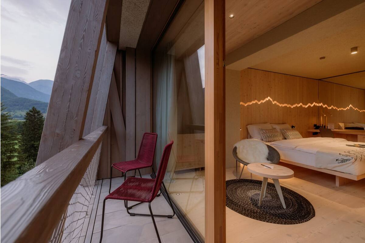 A modern bedroom with a bed, bedside table, and a view of the outdoors.