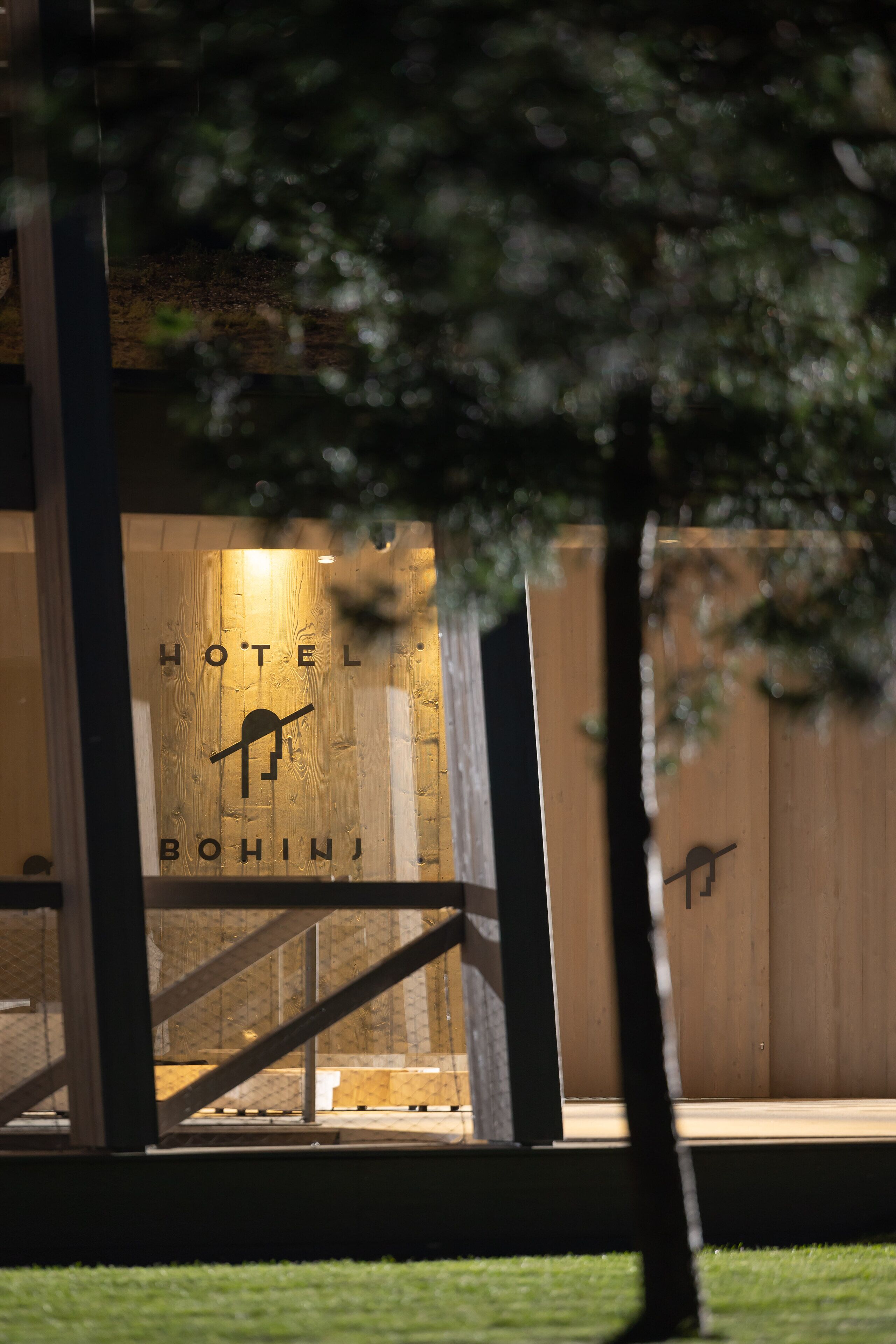 Entrada de un hotel con fachada de madera y un letrero que dice "HOTEL BOHINJ".