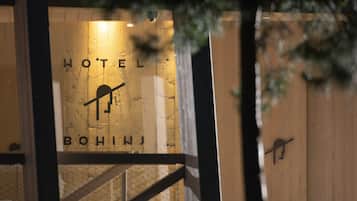 Entrada de un hotel con fachada de madera y un letrero que dice "HOTEL BOHINJ".