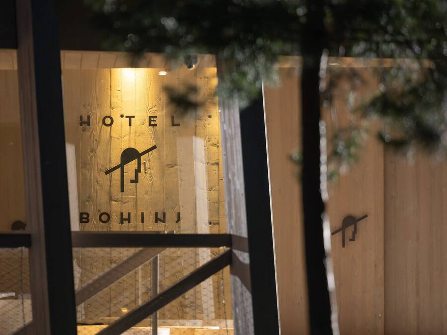 Entrada de un hotel con fachada de madera y un letrero que dice "HOTEL BOHINJ".