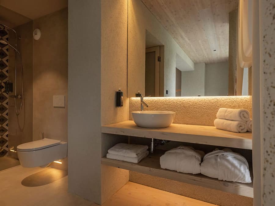 A modern bathroom with a walk-in shower, a toilet, a sink with a large mirror, and neatly folded towels on the counter.