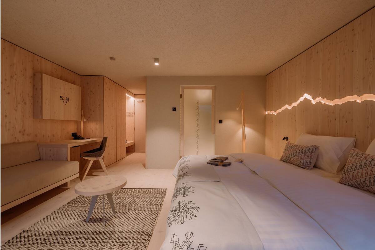 A modern bedroom with a bed, a desk, and a sofa.