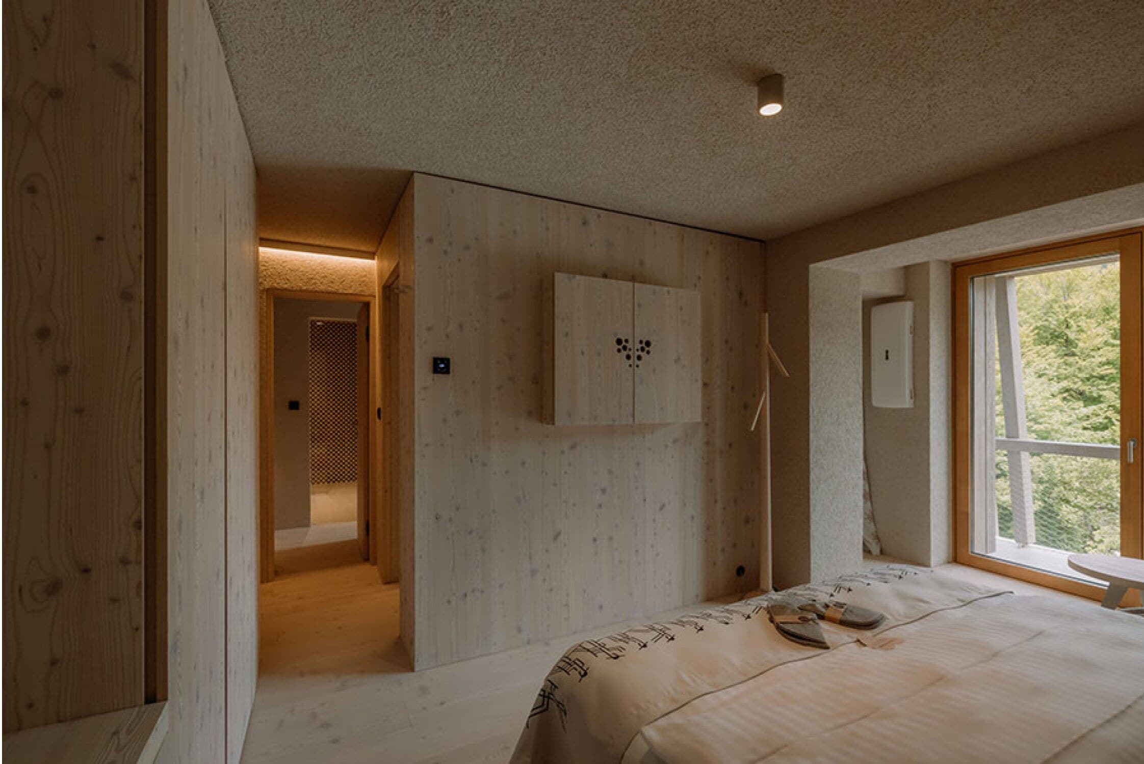 Un dormitorio con cama, armario, ventana y puerta que da a otra habitación.