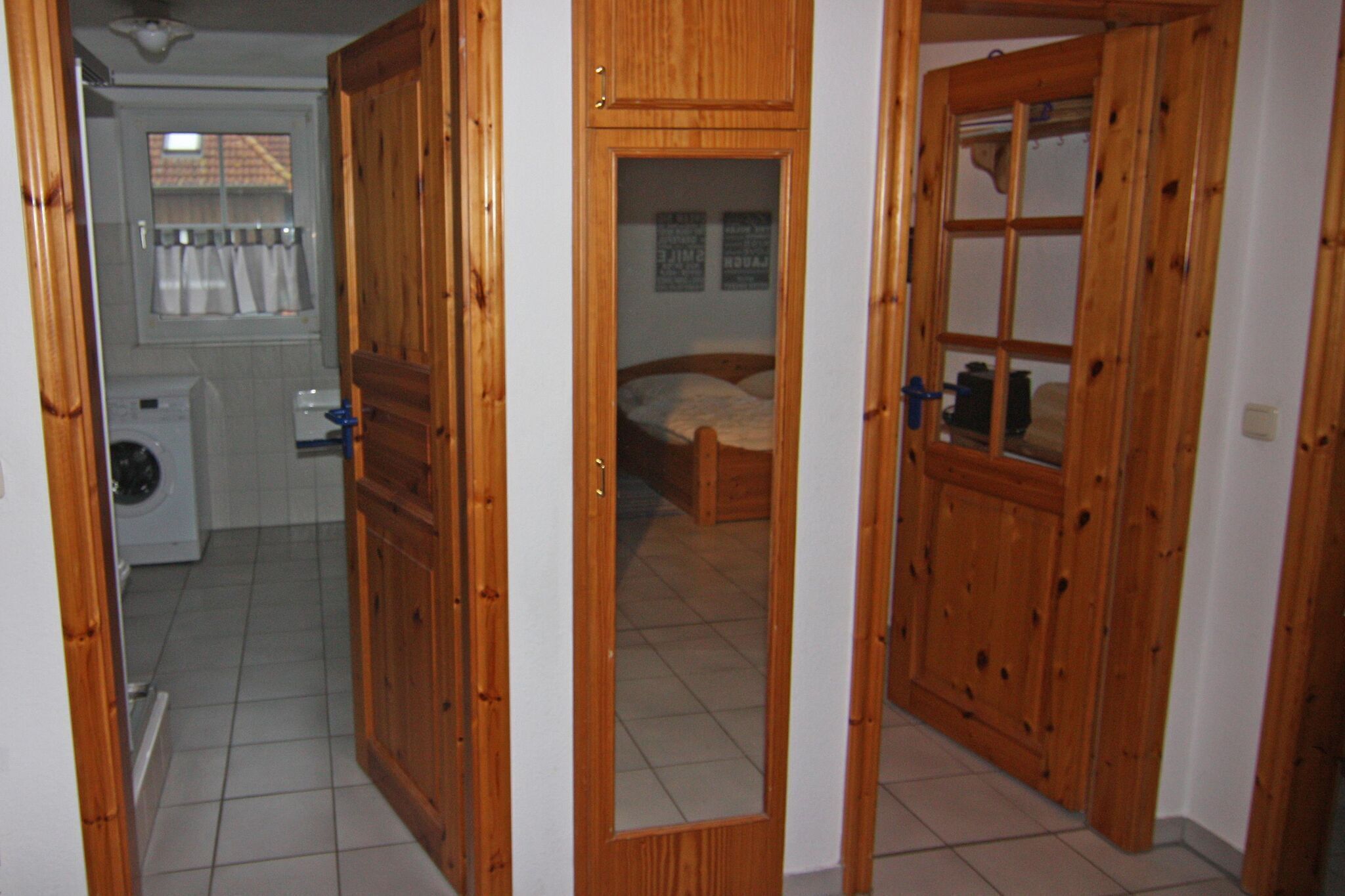 Een gang met houten deuren die leiden naar een slaapkamer en een wasruimte.