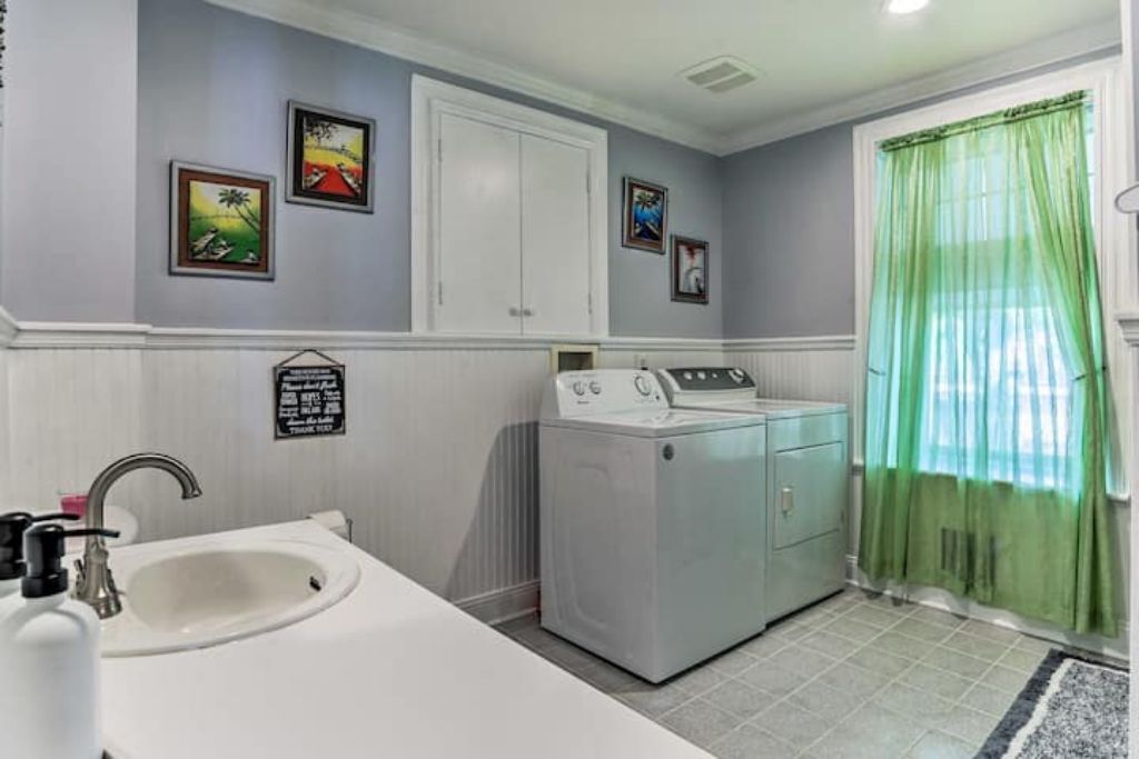 A laundry room with a washing machine, a sink, and a cabinet.
