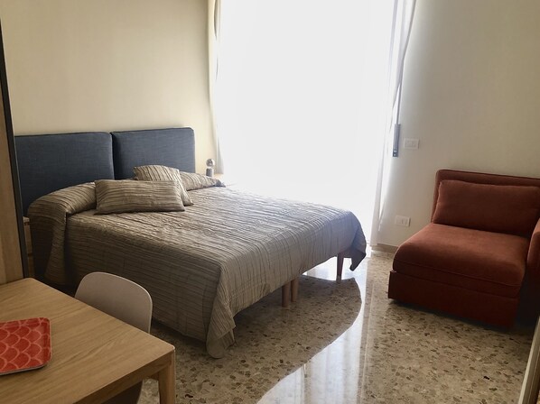 A bedroom with a bed, a chair, a table, and a window. - Attic "Space to Light" (Verona)
