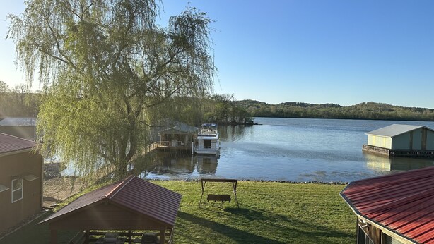Een gelegenheid aan het meer met een steiger, een boot en een gazon met een tuinhuis.