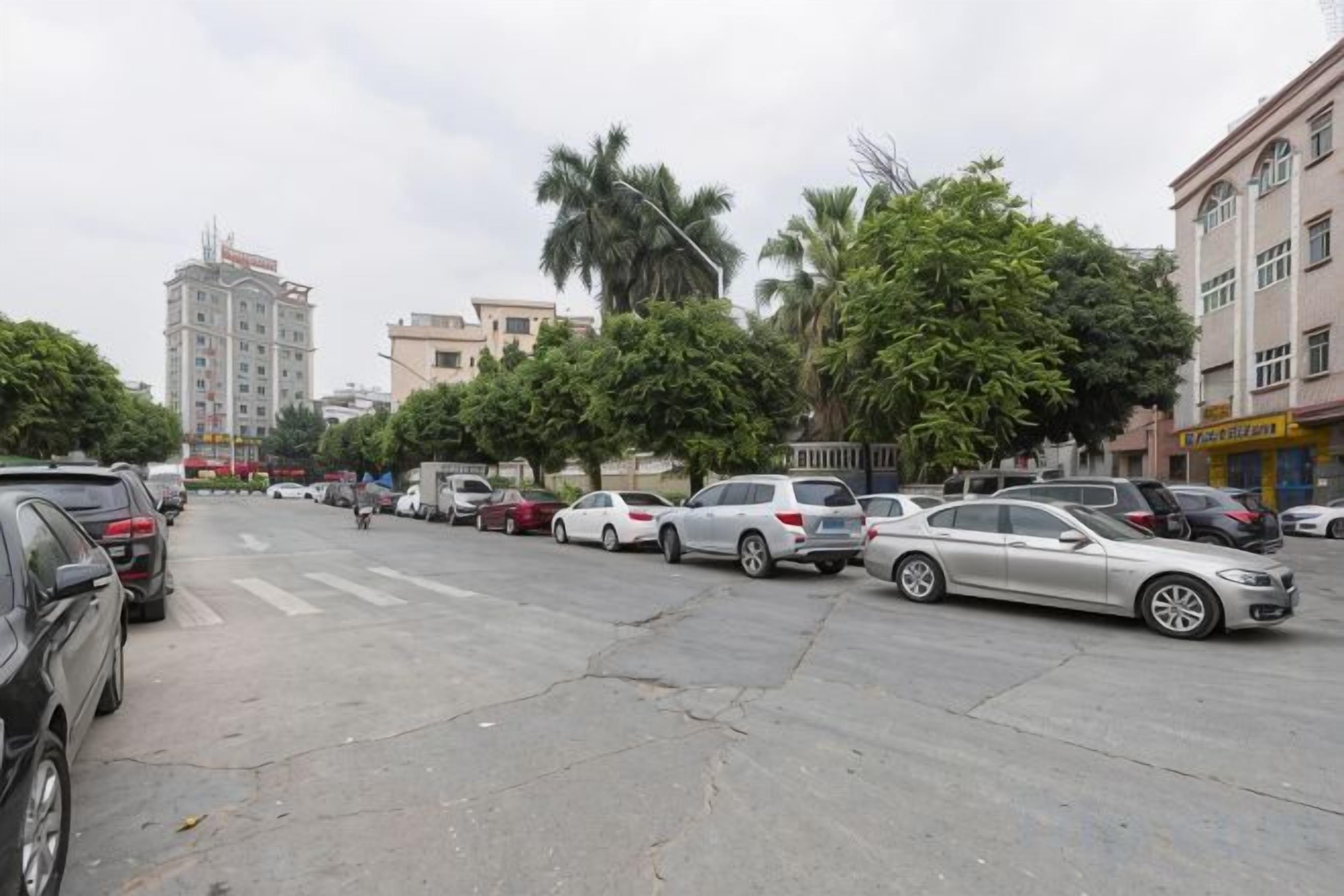 Um estacionamento com vários carros, uma faixa de pedestres e edifícios ao fundo.