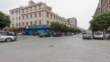 Una calle con edificios, coches aparcados y algunos peatones.
