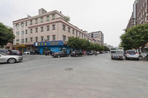 A street with buildings, parked cars, and a few pedestrians. - Dongguan Xinyi Business Hotel (Xingtai Academy) (Dongguan)