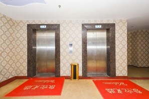 Two elevators with a patterned wall and a red carpet in the lobby area. - Dongguan Xinyi Business Hotel (Xingtai Academy) (Dongguan)