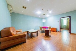 A spacious living area with a brown leather sofa, a wooden coffee table, and a dining table with chairs. - Dongguan Xinyi Business Hotel (Xingtai Academy) (Dongguan)