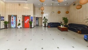 Un vestíbulo amplio con mostrador de recepción, zona de estar y una puerta roja con la leyenda 'OYO'.