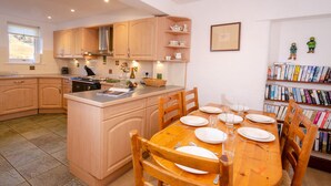 Een moderne keuken met houten kasten, een centraal eiland en een eethoek met een houten tafel en stoelen.
