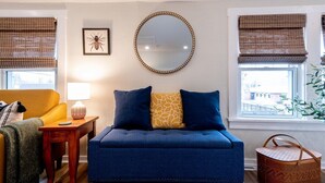 A living room with a blue sofa, a round mirror, and a yellow armchair. - The Back Yard-Upper Near Downtown LG |Balcony |Yard Now Dog Friendly (Lake Geneva)
