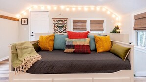 A cozy bedroom with a bed, colorful pillows, a blanket, and string lights. - The Back Yard-Upper Near Downtown LG |Balcony |Yard Now Dog Friendly (Lake Geneva)