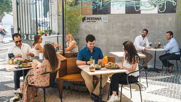 An outdoor dining area with tables and chairs, a sign for PESTANA HOTEL GROUP, and a QR code.