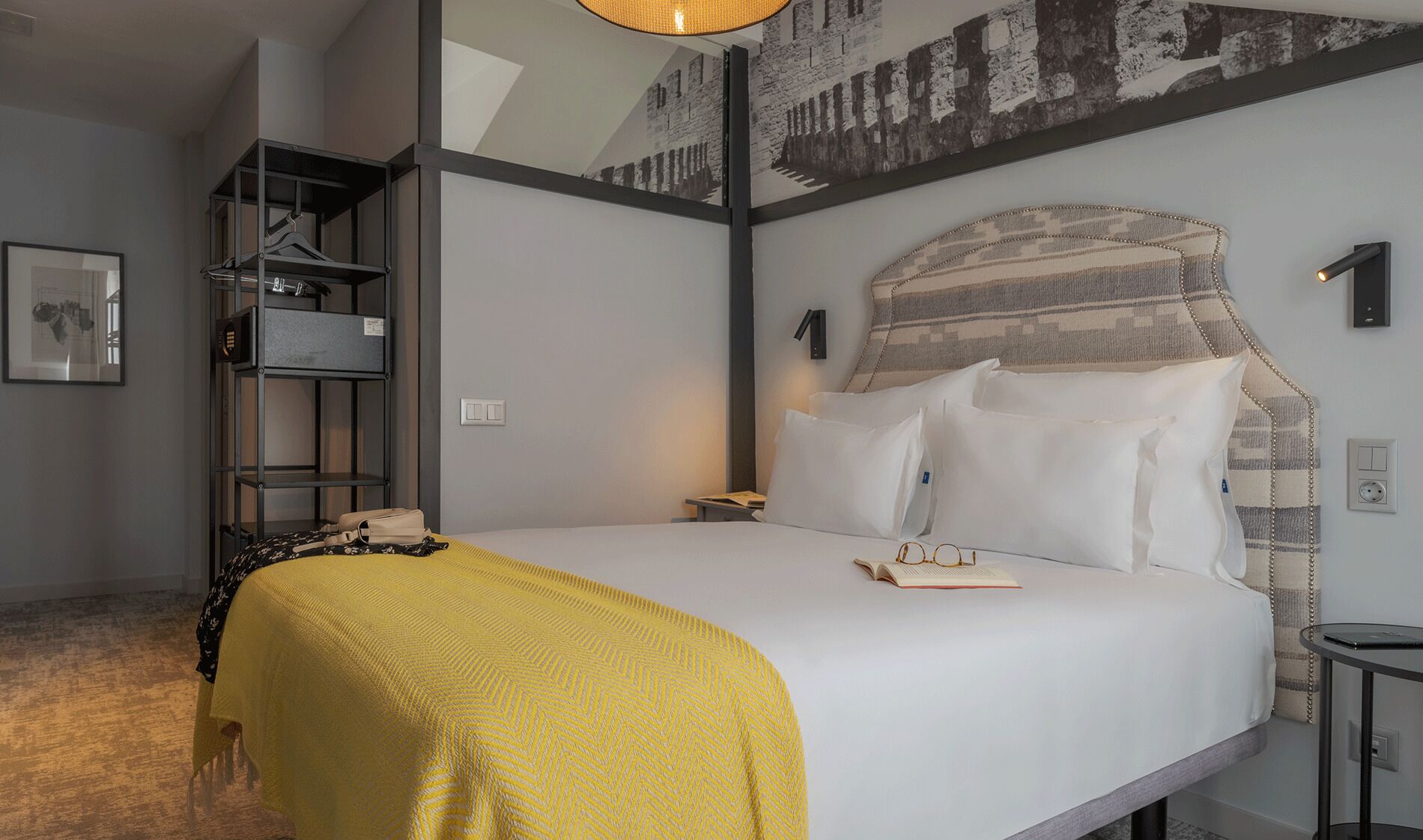 Een moderne hotelkamer met een groot bed, een nachtkastje, een lamp en een wandplank.