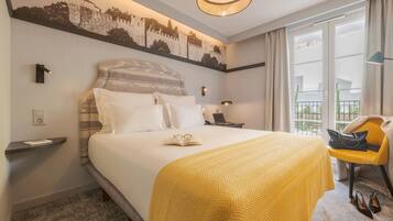 Une chambre d’hôtel avec un grand lit, une table de chevet, une chaise, un bureau avec une lampe et une vue sur l’extérieur.