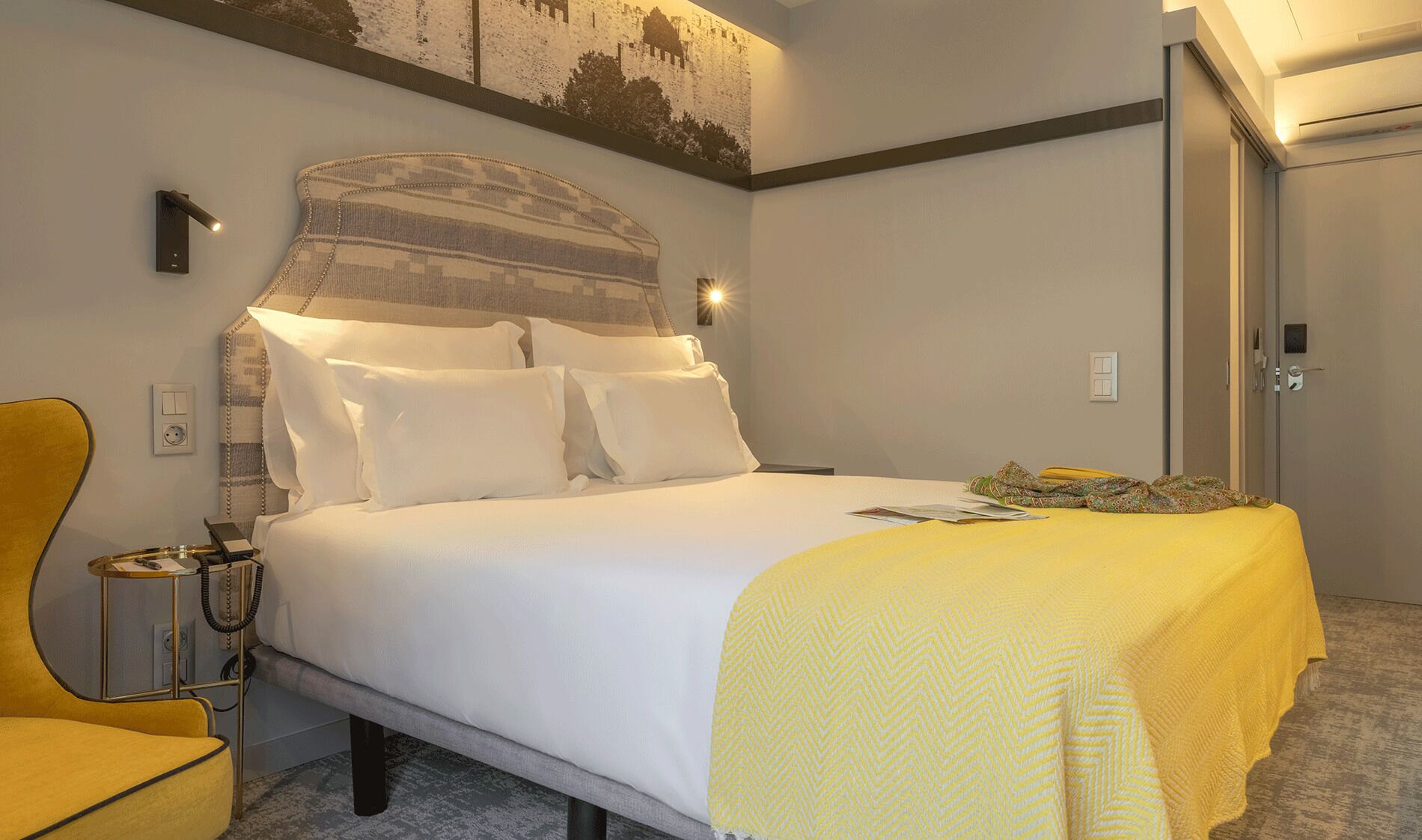 Ein Hotelzimmer mit einem Bett, einem Nachttisch, einem Telefon und einem Sessel.