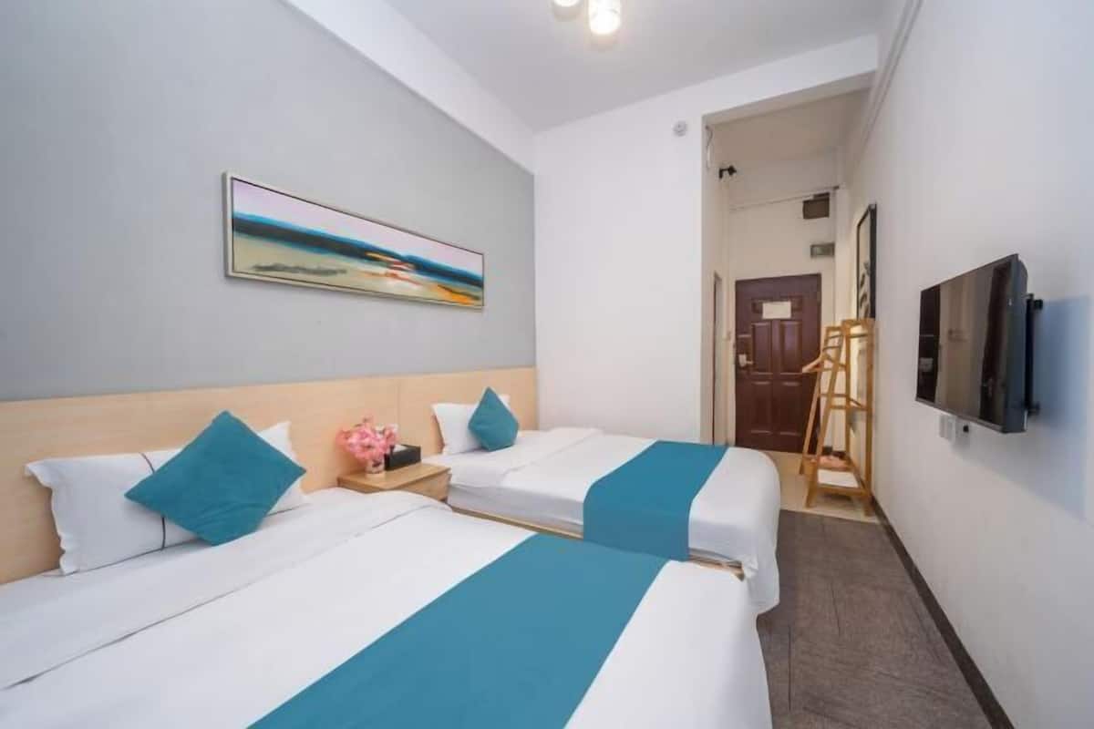 A hotel room with two beds, a painting on the wall, a television, and a wooden ladder.