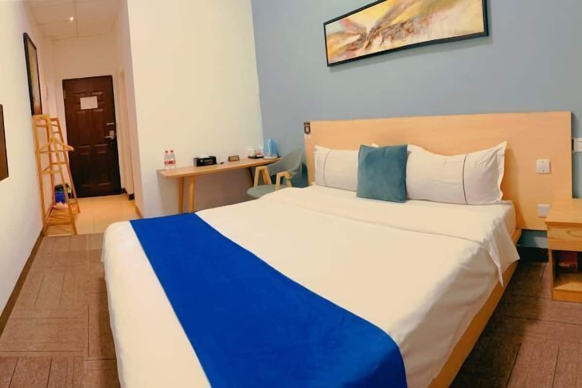 A hotel room with a bed, a desk, a chair, a ladder, and a door.