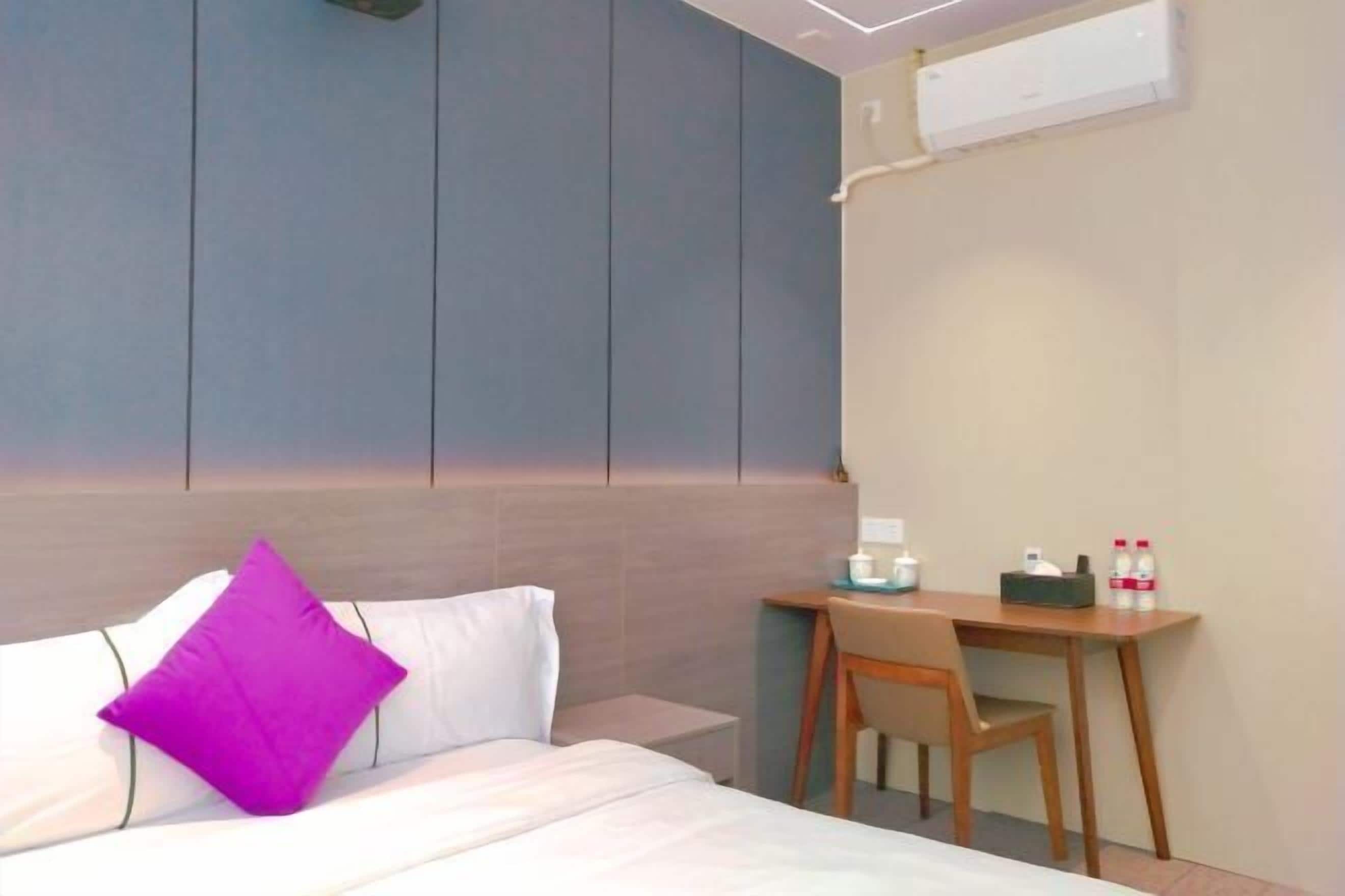 A hotel room with a bed, a desk, and a chair.