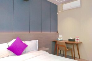 Ein Hotelzimmer mit Bett, Schreibtisch und Stuhl.