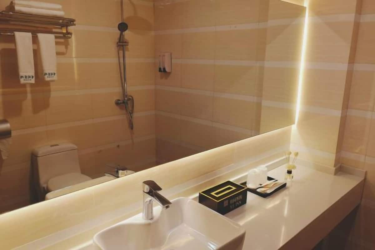 A bathroom with a sink, mirror, towel rack, and shower.
