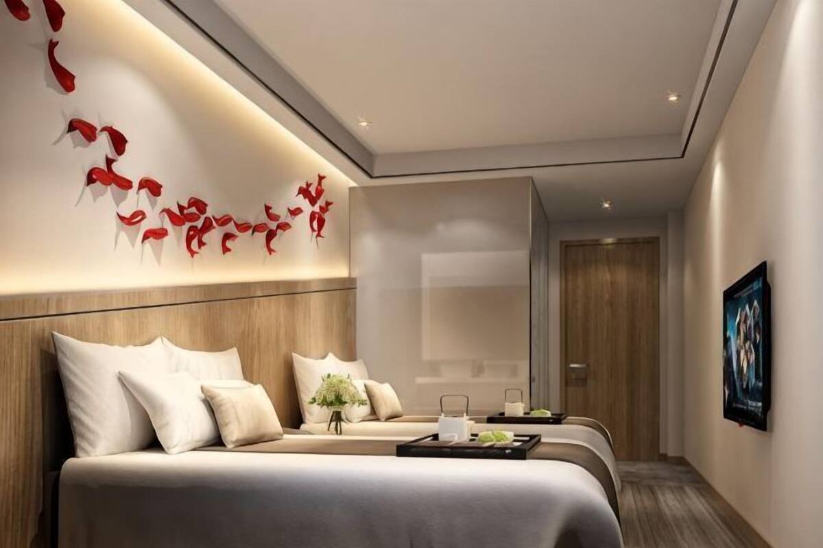 A hotel room with a bed, bedside tables, a wall-mounted artwork, and a door.