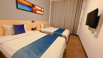 Een hotelkamer met twee bedden, een televisie en een schilderij aan de muur.