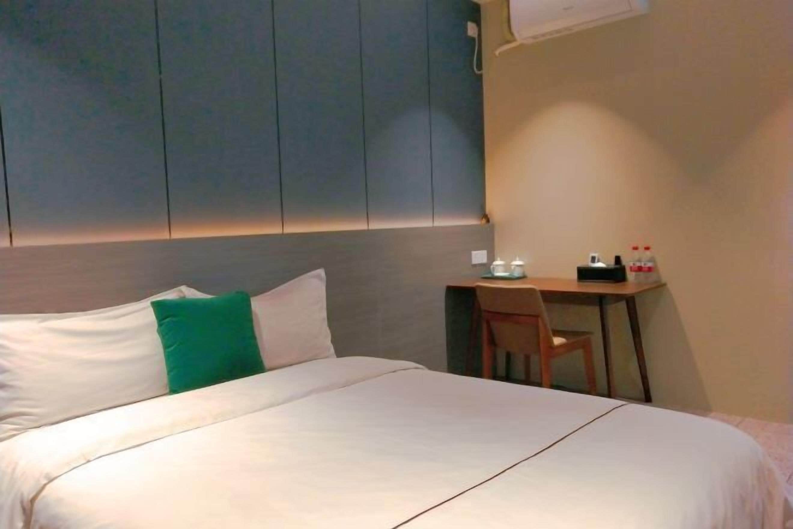 A hotel room with a bed, a desk, and a chair.