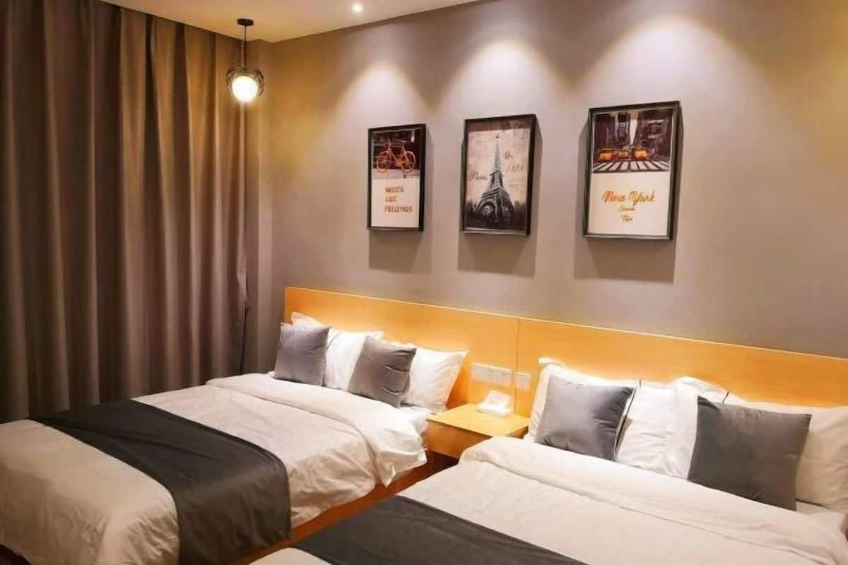 A hotel room with two beds, a nightstand, a lamp, and three framed pictures on the wall.
