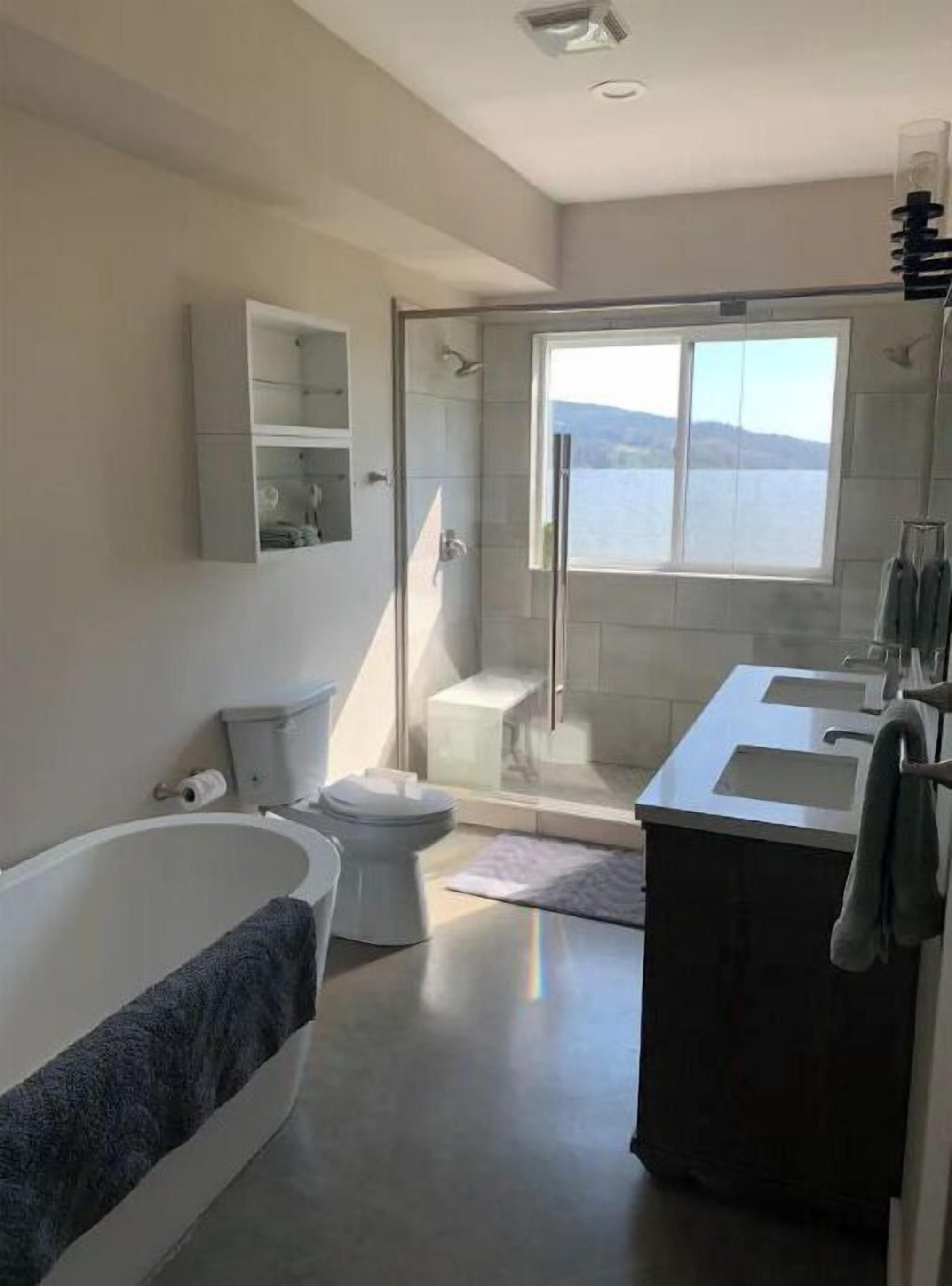 Een moderne badkamer met een bad, toilet en douche.