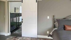 A bedroom with a bed, a headboard, a bedside table, a nightstand, a dresser, a mirror, a door with a sliding barn door, and a carpet. - Luxury shome, views above Skagit Valley- EV charge (Mount Vernon)