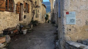 Un callejón estrecho con edificios de piedra antigua, un cartel que indica 'Calade de la SoleilLade' y un banco.