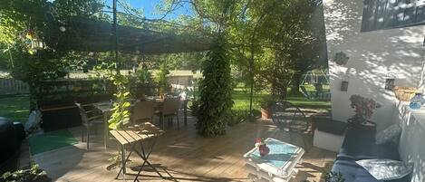 An outdoor patio with wooden flooring, a pool table, and seating areas.