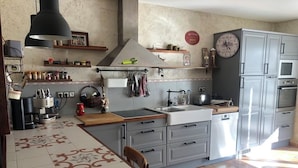Una cocina con una mesa de comedor, armarios, un reloj y varios electrodomésticos.