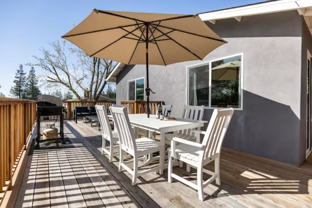Une terrasse avec une table et des chaises, un parasol et un espace barbecue.