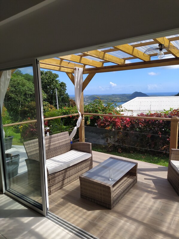 A patio with wicker furniture, a glass door leading outside, and a view of a mountainous landscape.