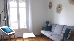 A living room with a grey sofa, a white armchair, a small table, and a floor lamp. - Apartment center Cannes (Cannes)