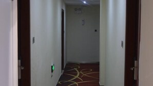 A narrow hallway with a patterned carpet, white walls, and doors on either side.