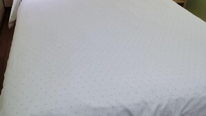 A bed with a white sheet and a dotted pattern.