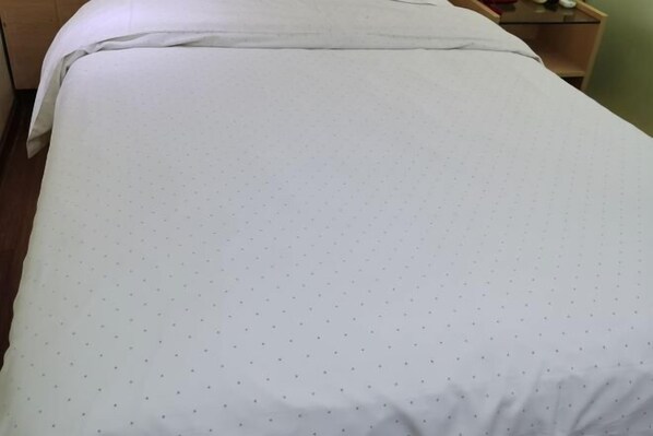 Un lit avec un drap blanc orné d'un motif à pois.