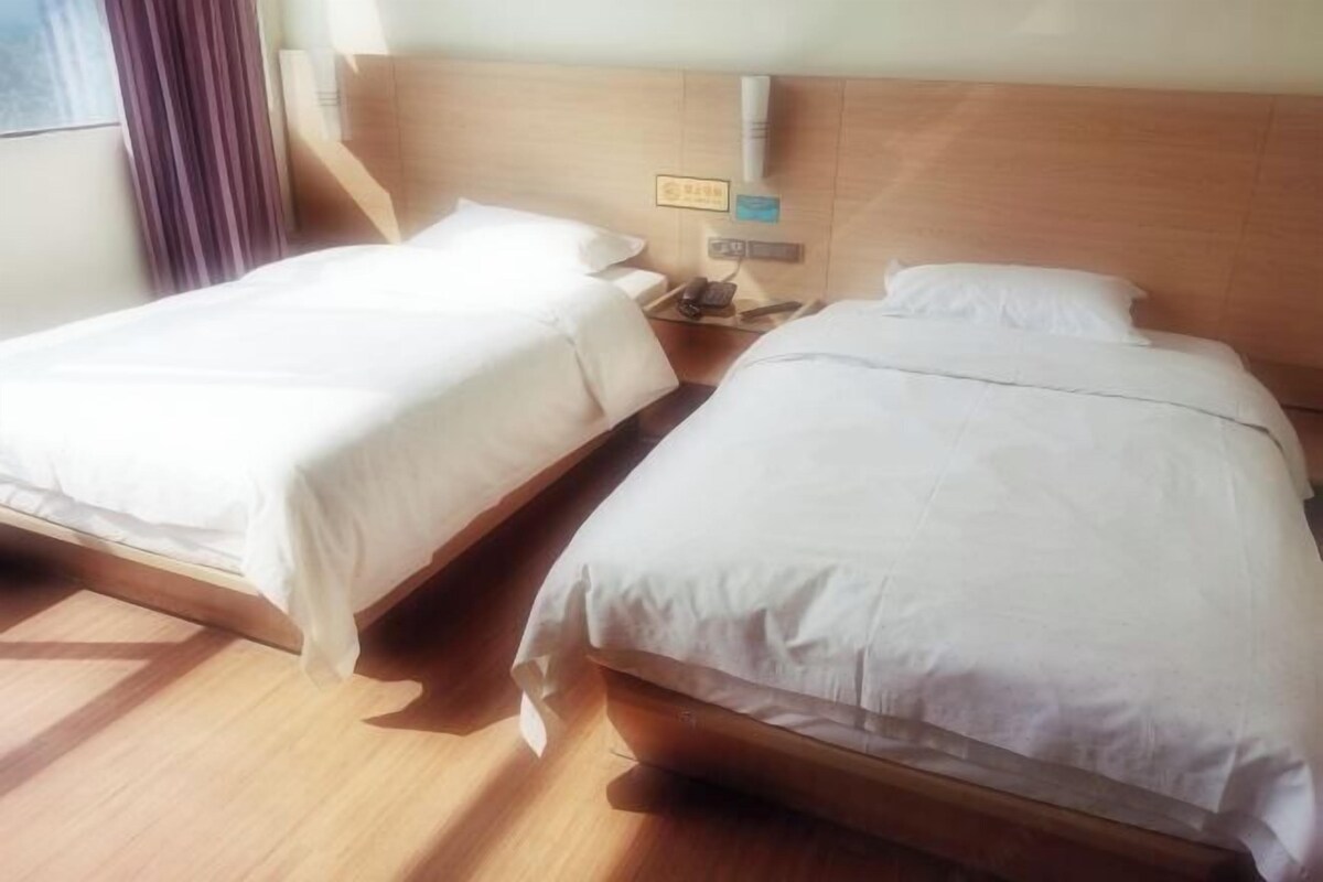 Deux lits simples avec des têtes de lit en bois dans une chambre d’hôtel.