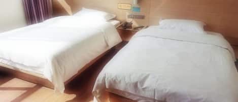 Two single beds with wooden headboards in a hotel room.