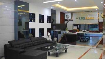 A modern living room with a black sectional sofa, a glass coffee table, and a flat-screen TV.