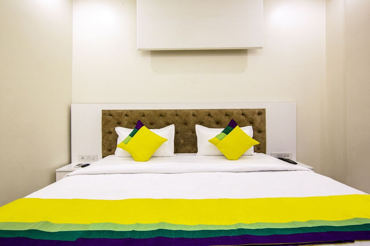 A bed with a tufted headboard, white bedding, and a rainbow-colored blanket.