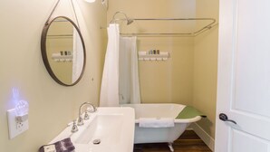 A bathroom with a sink, mirror, bathtub, and shower curtain.