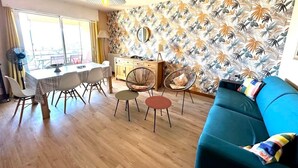 A modern living room with a dining area, a sofa, and a kitchen in the background. - T2 in the heights of Ajaccio golf view sea (Ajaccio)
